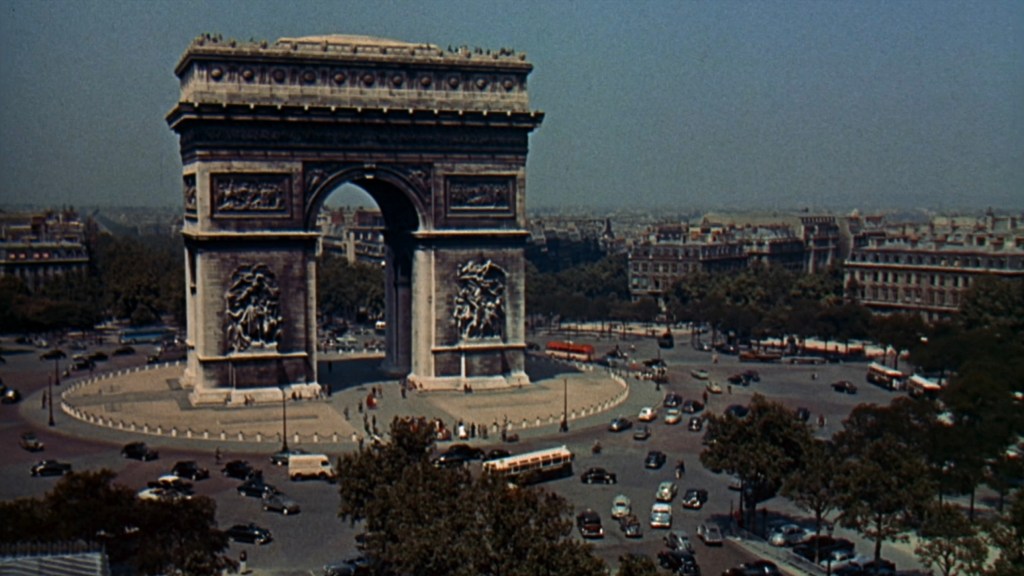 Aerial view of the Arc de Triomphe in Paris, surrounded by traffic and trees on a clear day.