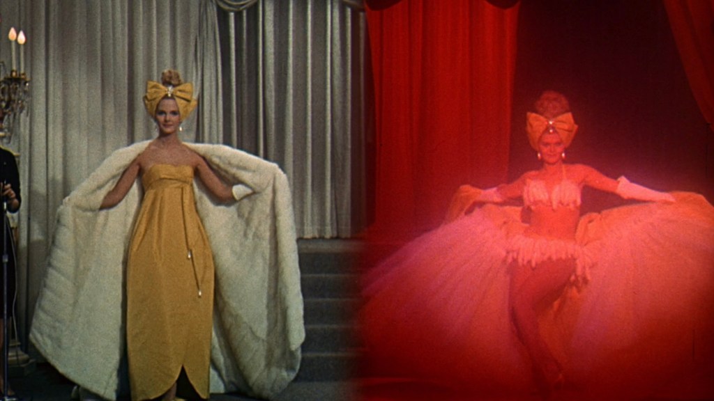 A fashion model showcasing a vibrant yellow gown and a large bow on her head, standing on stage with a dramatic fur coat.