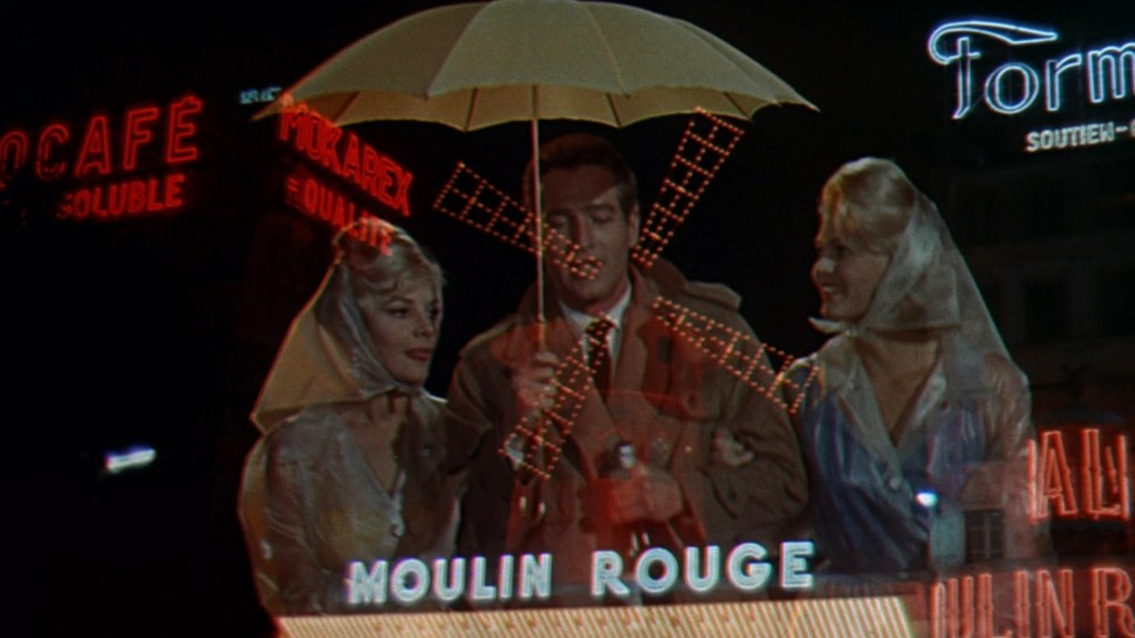 A scene featuring two women in raincoats and a man holding an umbrella, with the illuminated 'Moulin Rouge' sign and neon lights in the background.