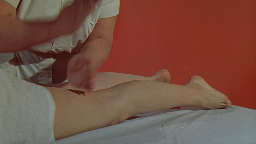 A person receiving a leg massage, with a focus on the lower leg and foot, against a red background.