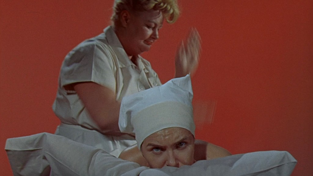 A woman receiving a massage while another woman in a white uniform is performing the massage in a brightly colored setting.