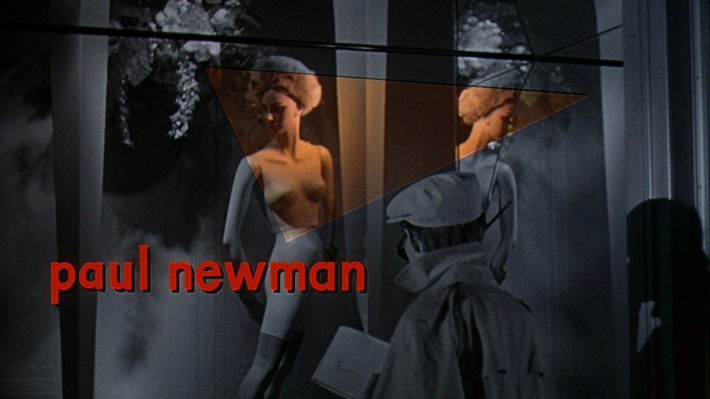 A vintage black and white image featuring mannequins in a display window, with the name 'Paul Newman' prominently displayed in red text.