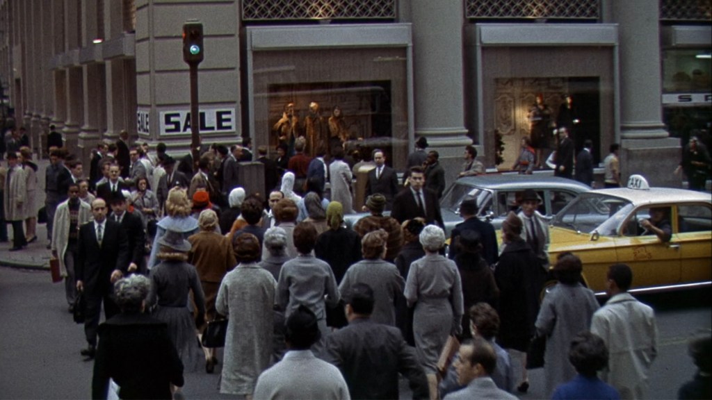 Busy urban street scene with pedestrians and a taxi, featuring a storefront with a 'SALE' sign and a crowd of people in fashionable attire.