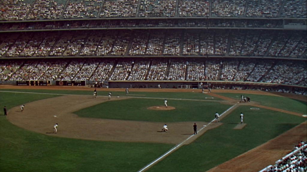 A panoramic view of a baseball stadium filled with spectators, showcasing a game in progress with players on the field and a vibrant crowd in the stands.