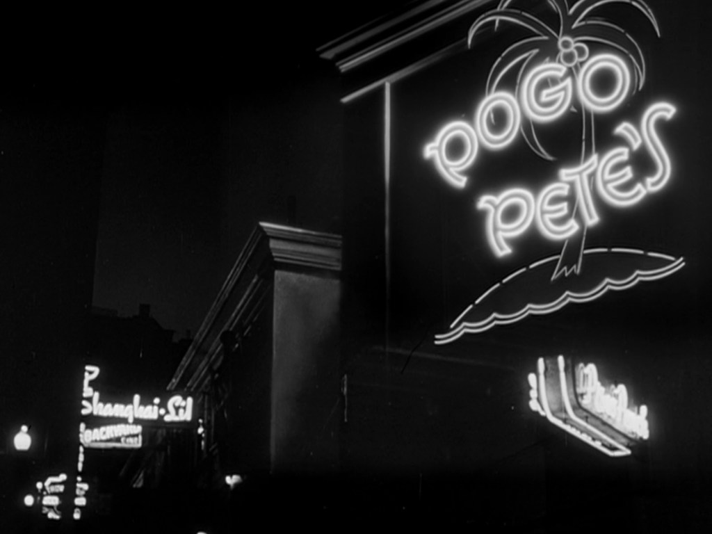 Neon sign for Pogo Pete's with palm tree design, visible in a nighttime urban setting.