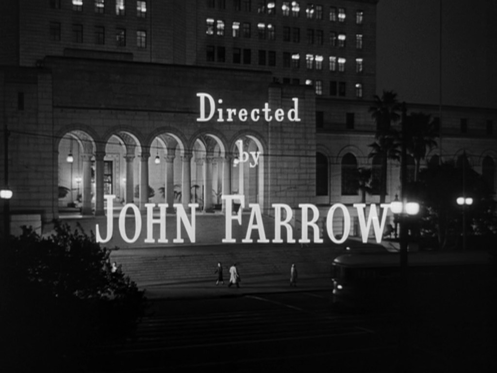 Film title card featuring the text 'Directed by John Farrow' against a nighttime city backdrop with a grand building and people walking.