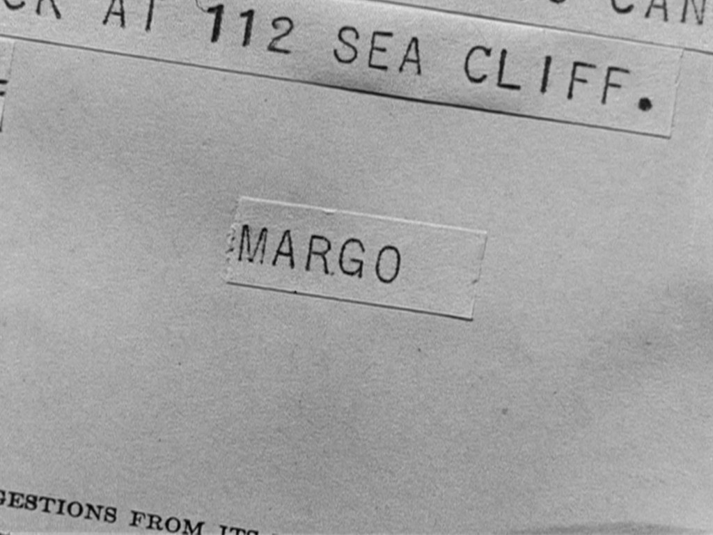 Close-up of a paper with the address '112 Sea Cliff' and the name label 'MARGO' affixed to it.