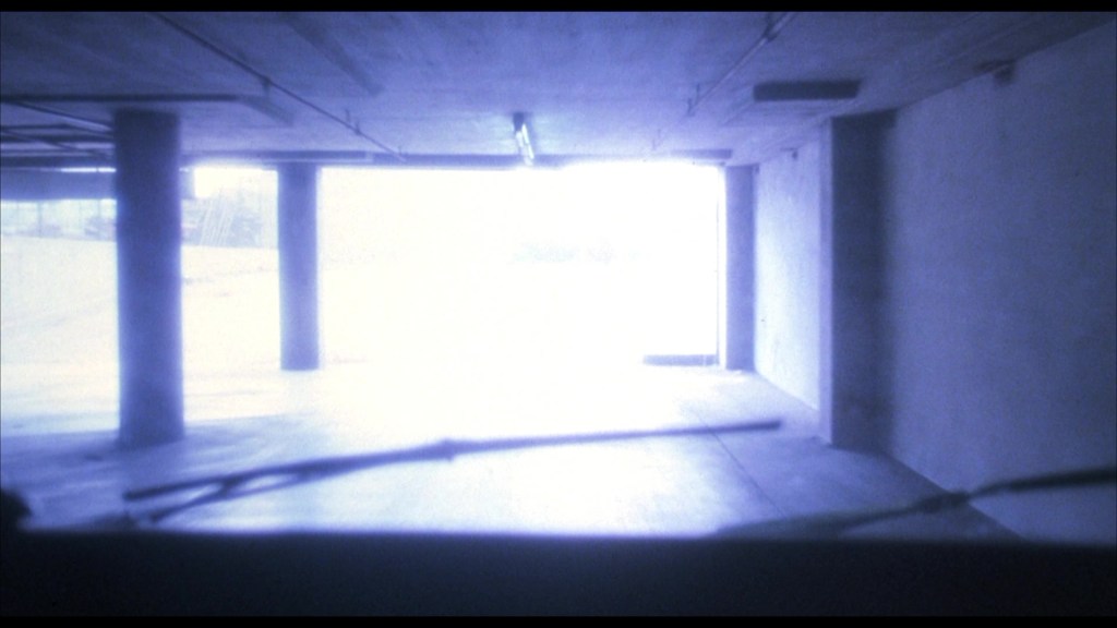 View of a dimly lit parking garage exiting into bright light.