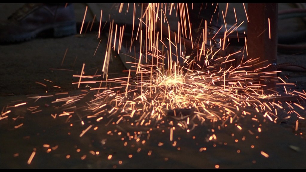 Sparks flying from metal being worked on in a workshop setting.