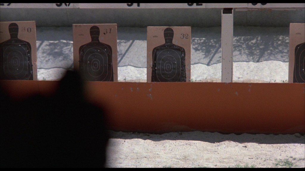 A shooting range displaying multiple targets placed on stands, with a blurred figure in the foreground.