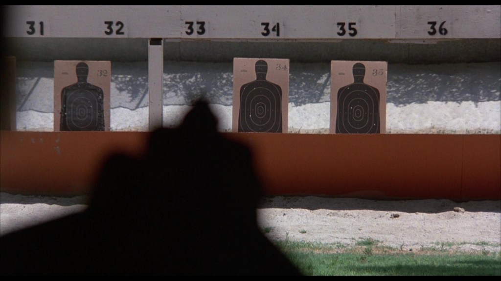 Silhouette of a firearm in the foreground with shooting targets lined up in the background, displaying numbers 31 to 36.