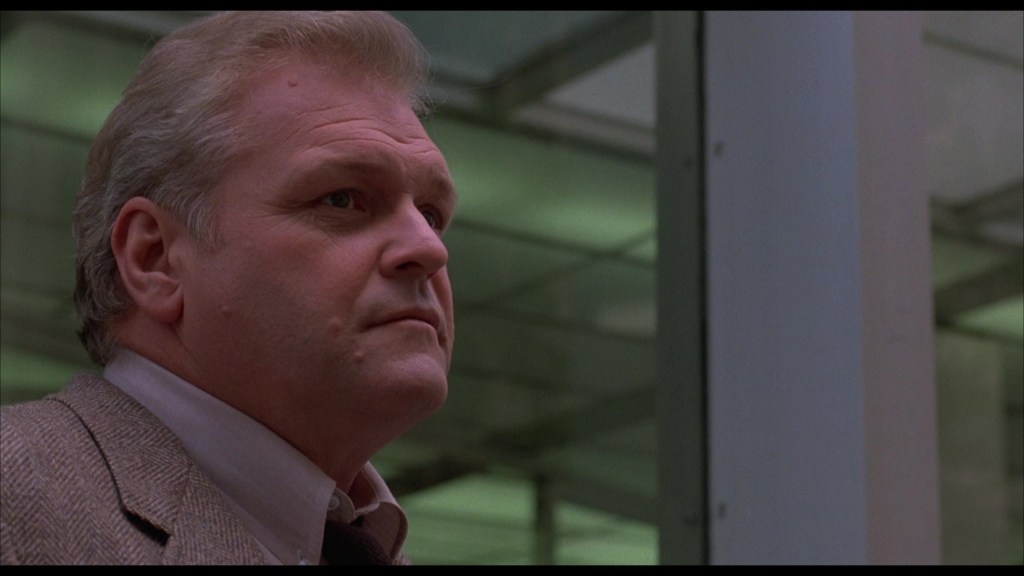 A close-up profile of a middle-aged man with gray hair, looking thoughtfully off to the side in a modern indoor setting.