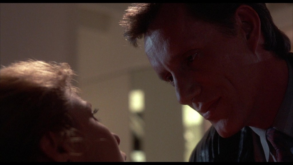 Close-up of a man and woman sharing an intimate moment, with dramatic lighting highlighting their facial expressions.