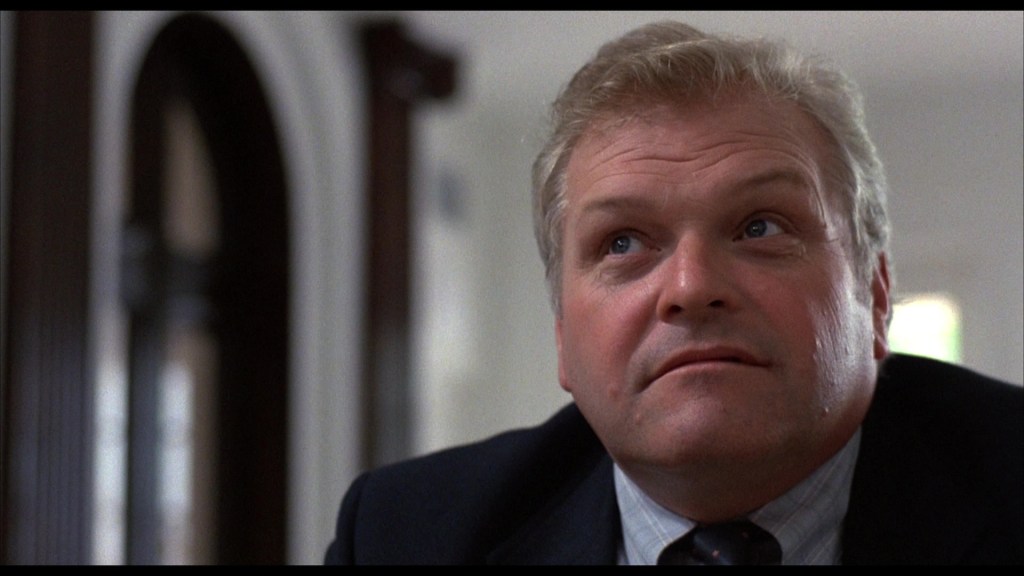 Close-up of a man with light hair, wearing a suit, looking upwards with a contemplative expression.