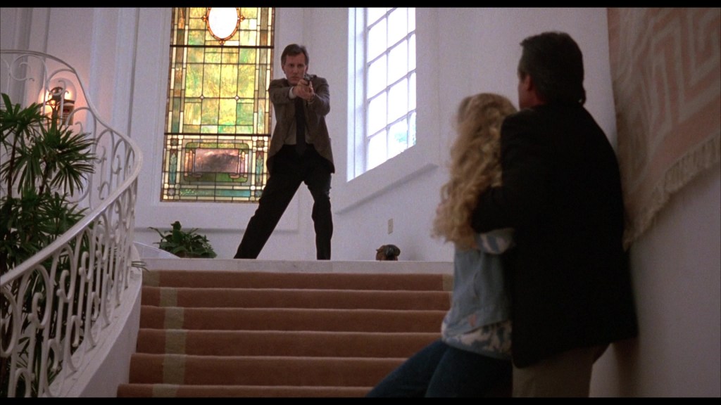 A tense scene depicting a man with a gun standing at the top of a staircase, while a woman and another man are crouched at the bottom, showing fear and apprehension.