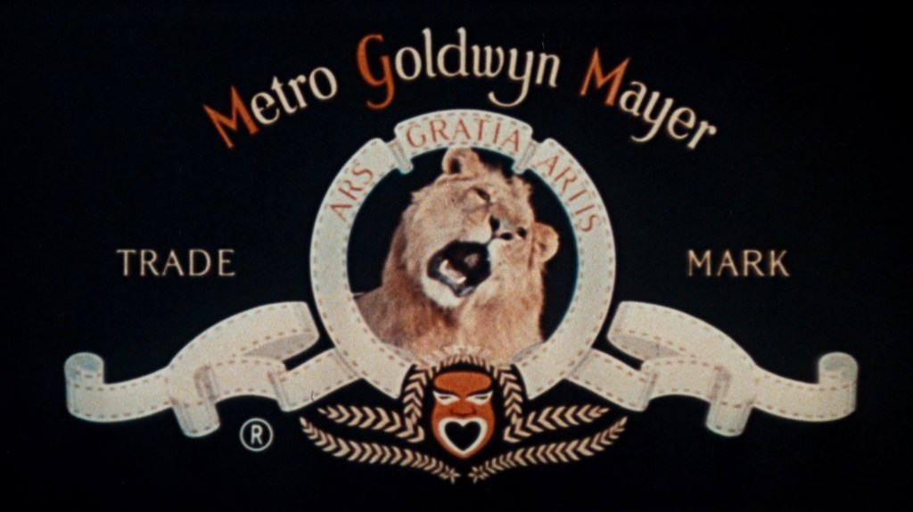 Metro Goldwyn Mayer logo featuring a roaring lion surrounded by decorative elements and the motto 'Ars Gratia Artis' on a black background.