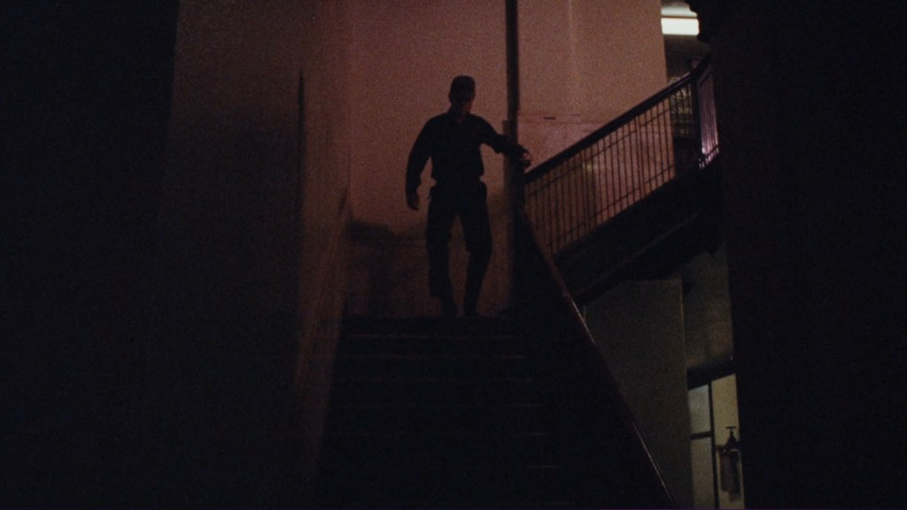 A shadowy figure descending a dimly lit staircase, creating a suspenseful atmosphere.