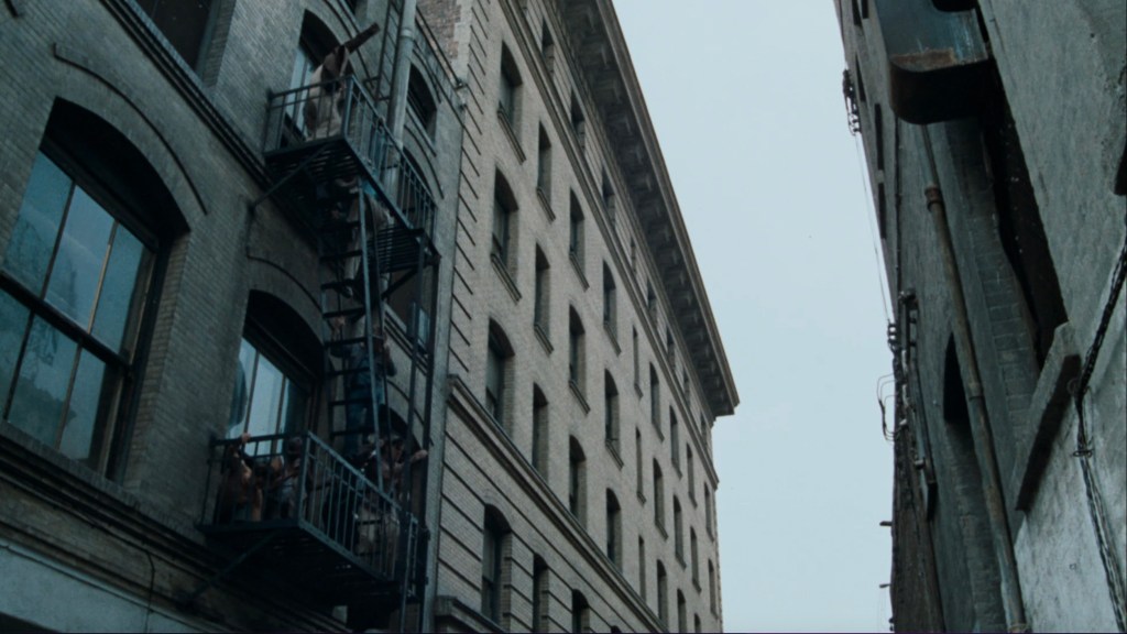 A view between two buildings showing a fire escape staircase, with figures visible on some balconies.