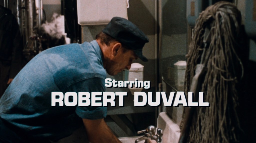 Scene with a man working at a sink, featuring the text 'Starring Robert Duvall' in bold, white font.