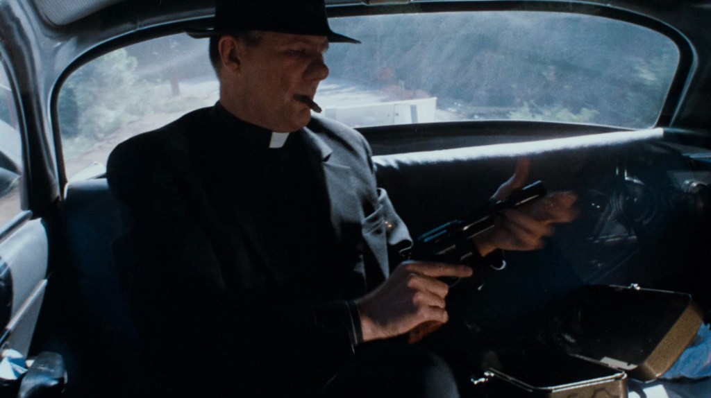 A man in a priest outfit, holding a gun and a cigar, seated inside a car, with a blurred forest view outside the window.