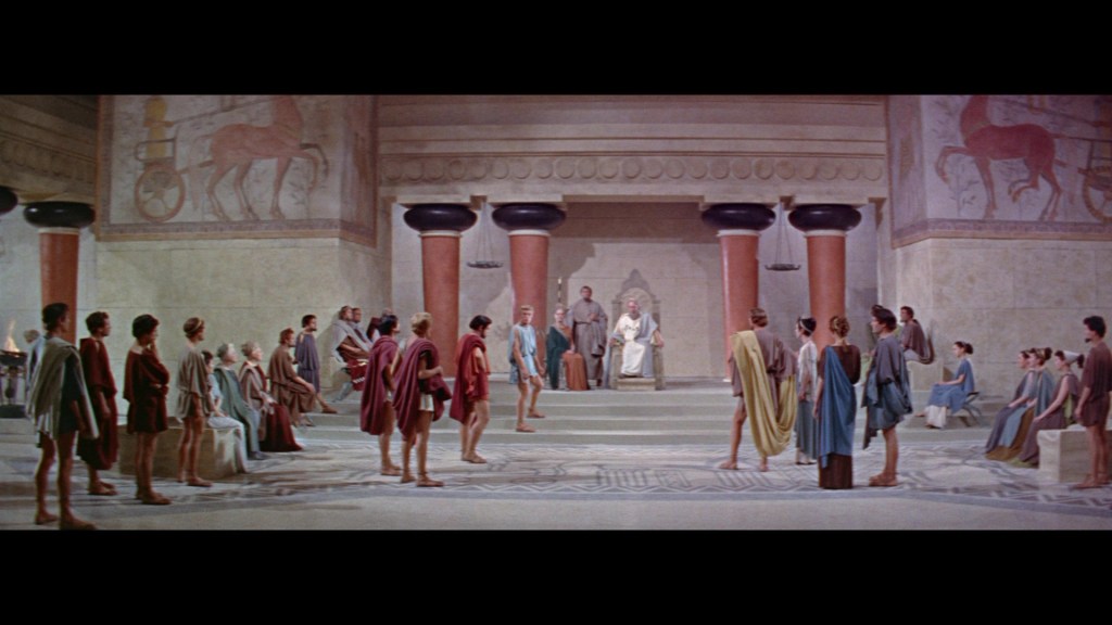 A scene depicting an ancient assembly with several figures in togas gathered around a central figure seated on a throne, set in an elaborately decorated hall with murals and large columns.