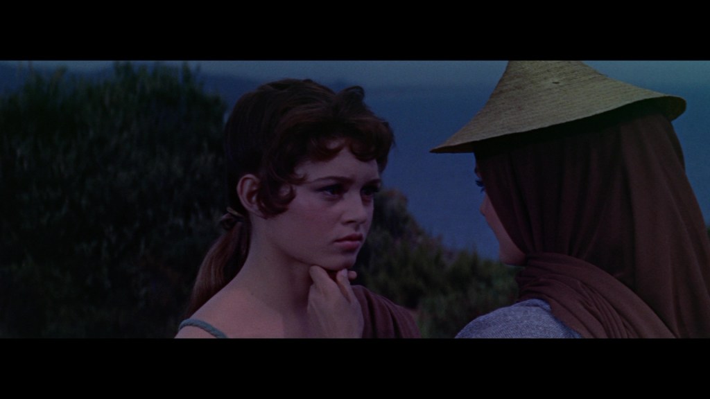 Two young women in a thoughtful conversation outdoors with a scenic background.
