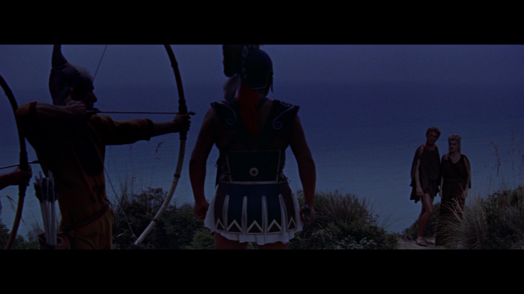 A warrior in armor with a helmet stands facing the ocean, with a bowman aiming an arrow in the background. Two figures dressed in ancient attire walk towards the warrior.