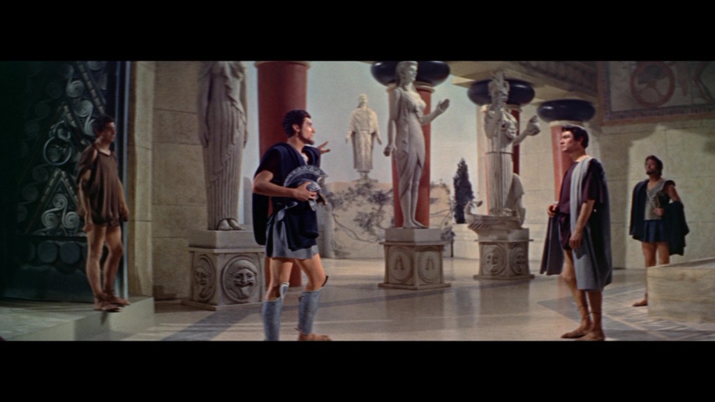 A scene depicting ancient Greek architecture with four men dressed in traditional attire, standing among classical statues in a spacious hall.