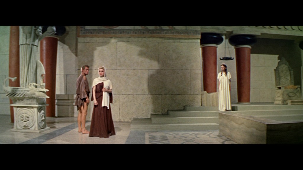 A scene set in an ancient Greek-inspired temple, featuring two characters in classical attire conversing, while a third character stands in the background, observing.