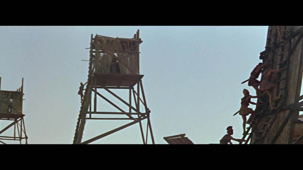 Silhouetted figures climbing wooden structures against a clear sky.