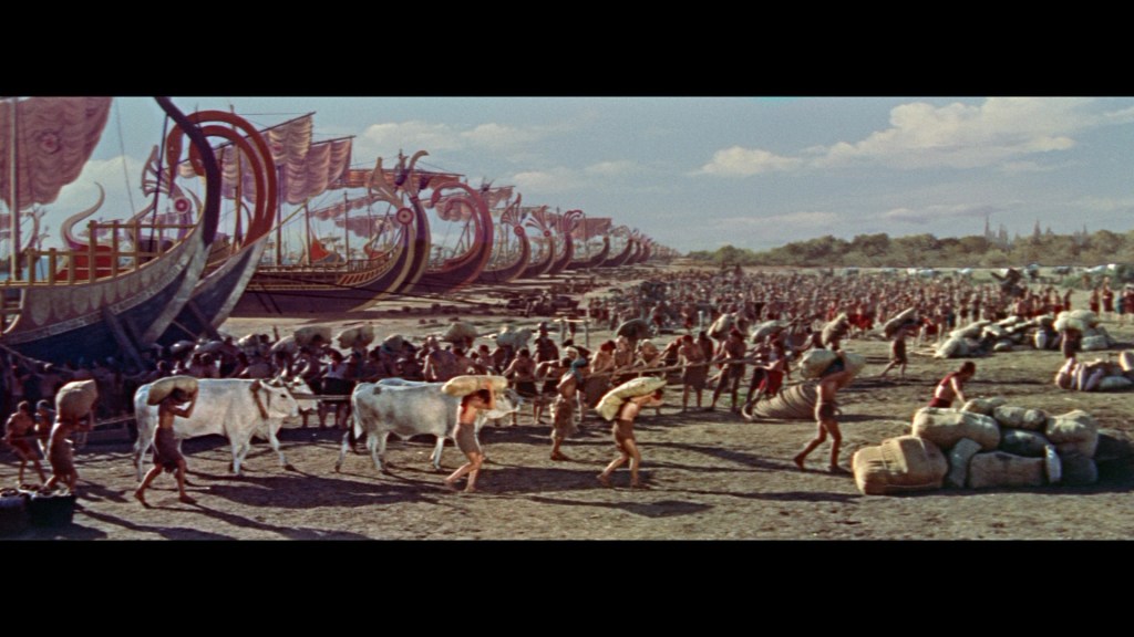 A bustling ancient port scene with a fleet of large ships in the background, workers loading animals and goods onto them, while a crowd of people fills the foreground.