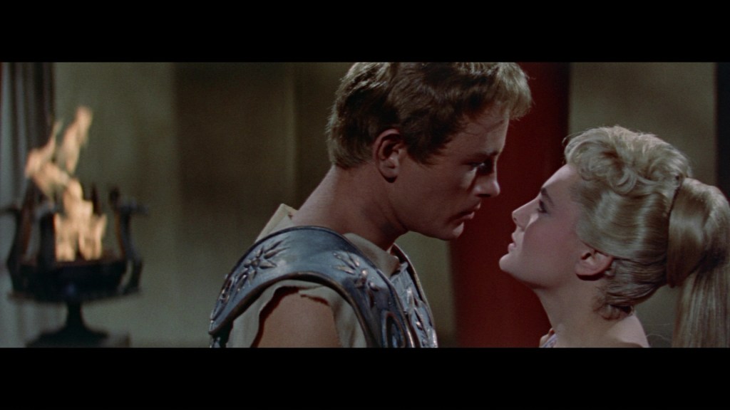 A close-up of two characters, a man and a woman, gazing into each other's eyes, with soft lighting and a warm background. A flame flickers in the background, adding to the romantic atmosphere.
