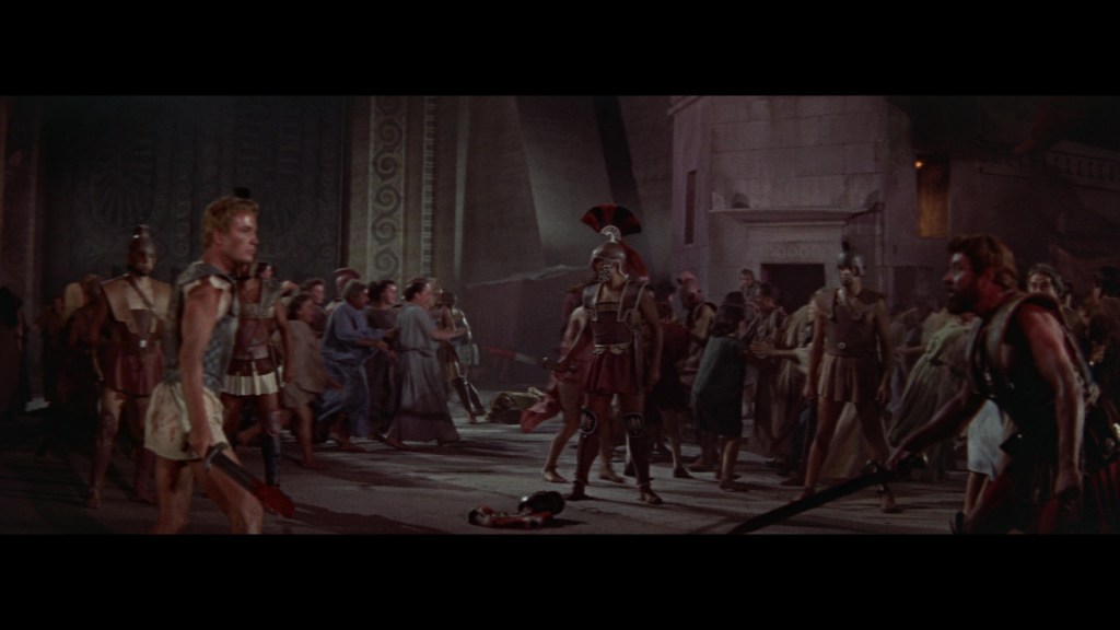 A dramatic scene depicting a chaotic fight in an ancient setting, with soldiers in armor, civilians in historical clothing, and weapons drawn.