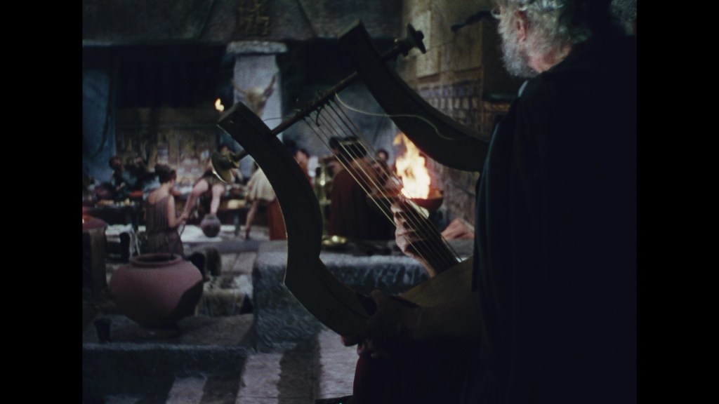 An ancient scene depicting a musician playing a lyre, surrounded by people in a lively gathering with pottery and a fire in the background.