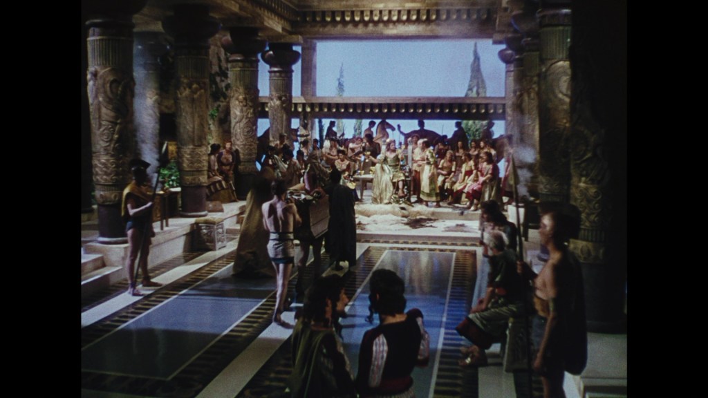 A vibrant scene set in an ancient temple, featuring a large gathering of people dressed in historical garments. Columns with intricate designs surround the space, with some individuals engaged in conversation while others stand attentively. The background includes a sky scene visible through the temple structure.