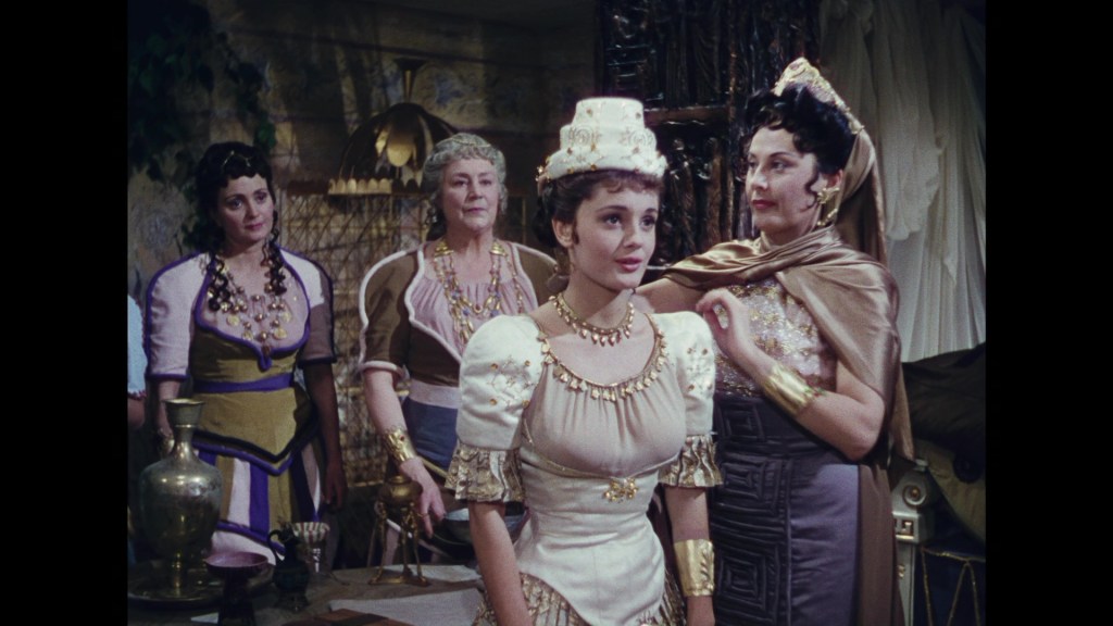 A group of four women dressed in historical costumes, with one woman in a prominent white dress adorned with jewels, surrounded by others in colorful attire, all set in a stylized room.