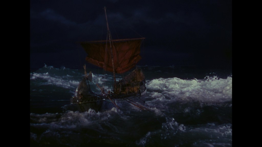 A small boat with a red sail navigating through stormy, turbulent waters at night under a dark sky.