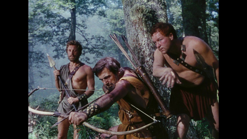 Three ancient warriors in a forest, one aiming a bow, while the others stand alert with weapons.