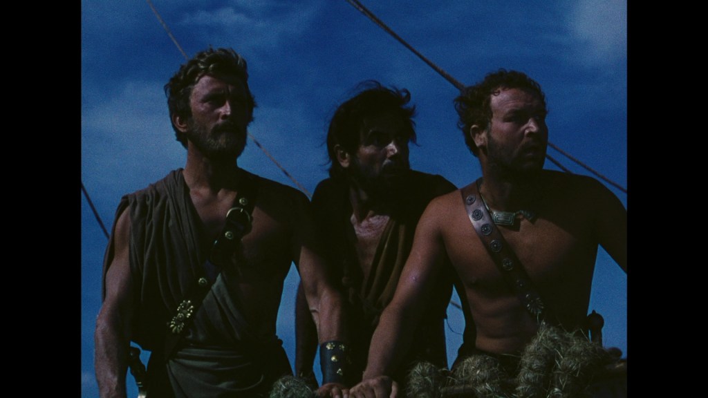 Three men on a ship looking out to the sea, wearing ancient Greek-style clothing, with a blue sky in the background.