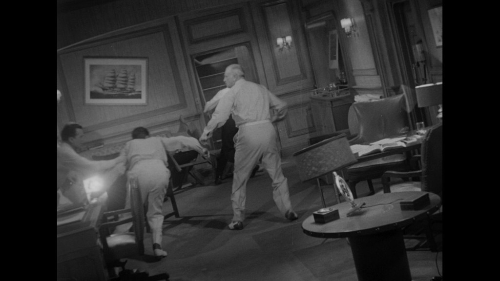 A chaotic scene in a room with several people, apparently in a state of agitation or distress, as furniture is displaced and the setting appears disheveled.