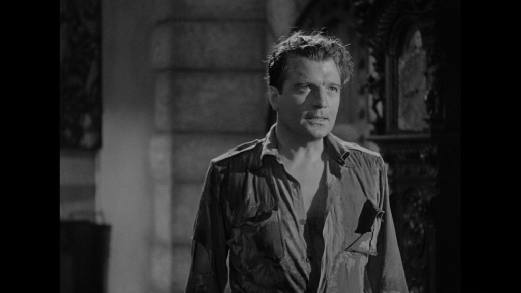 A man in a disheveled, wet shirt stands in a dimly lit room, looking serious, with a background featuring an ornate structure.