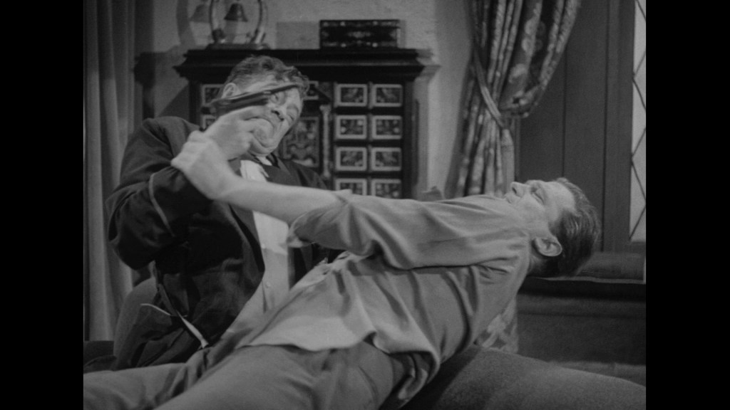 A tense scene depicting a struggle between two men, one holding an object while grappling with the other on a sofa in a living room setting.