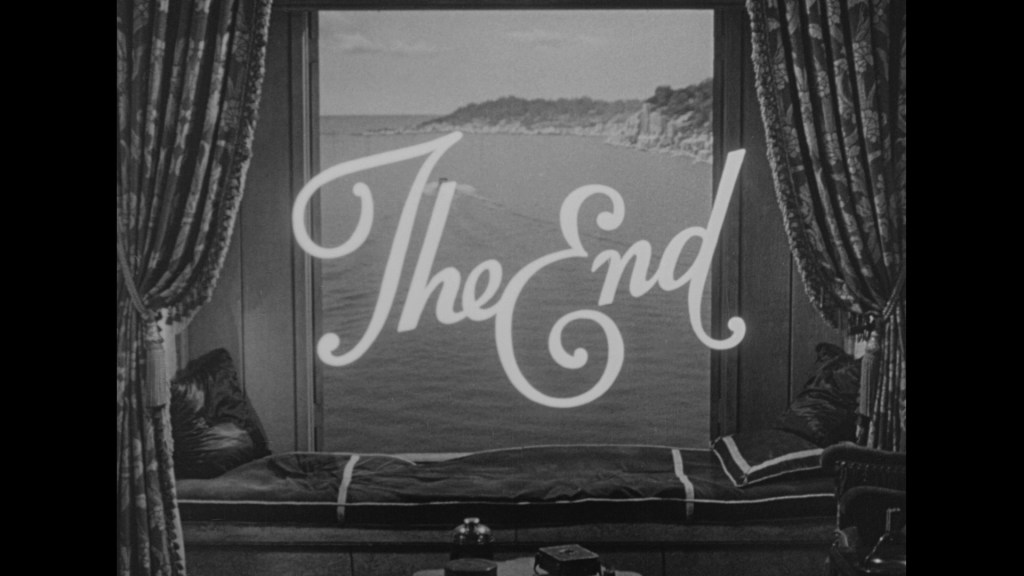 A black and white image featuring the words 'The End' prominently displayed in a stylized font, set against a backdrop of a seaside view visible through a large window, with luxurious curtains on either side.